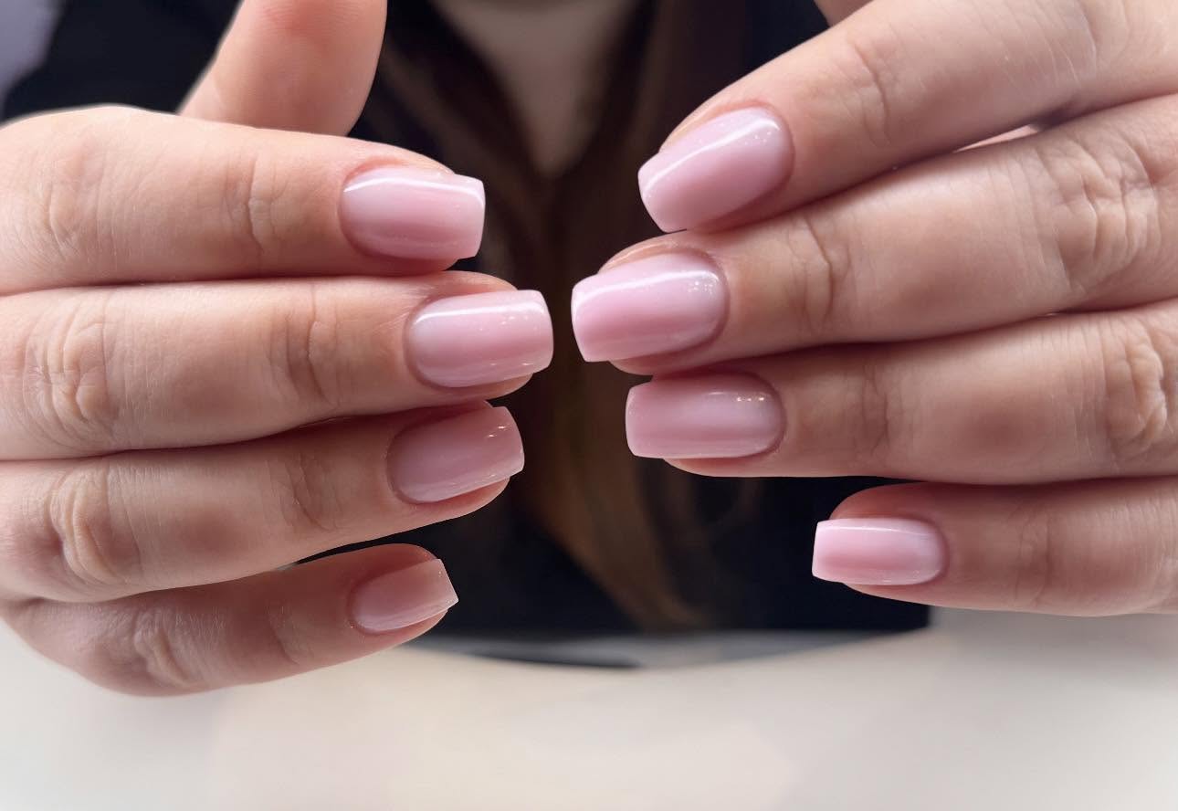 Dwie dłonie z kwadratowym manicure w pastelowym różu